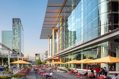 Street view of The George R. Brown Convention center facade showing the new curtain wall and exterior features with people seated in the foreground.