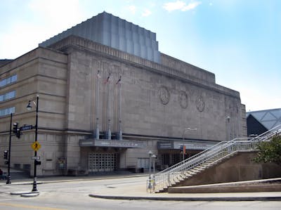 A northern view of Kansas City's historic auditorium, which features three inlaid and carved medallions, and an entryway topped with three flag staffs.