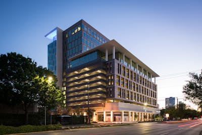 Street view of One Grove Street building lit up at dusk.