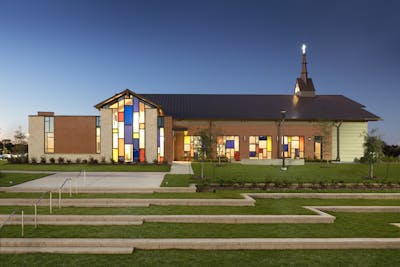 Outside of the Star of Hope Cornerstone Community Campus building with stained glass windows lit up at night.